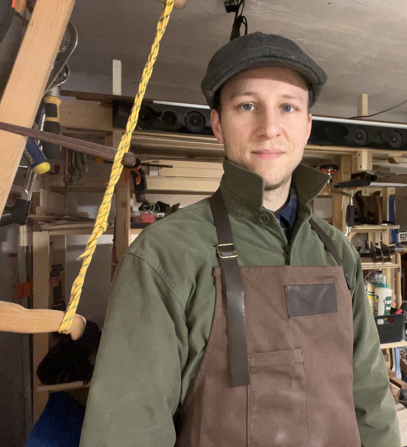 Timothy Perdue in the workshop, wearing a work apron beside hand tools
