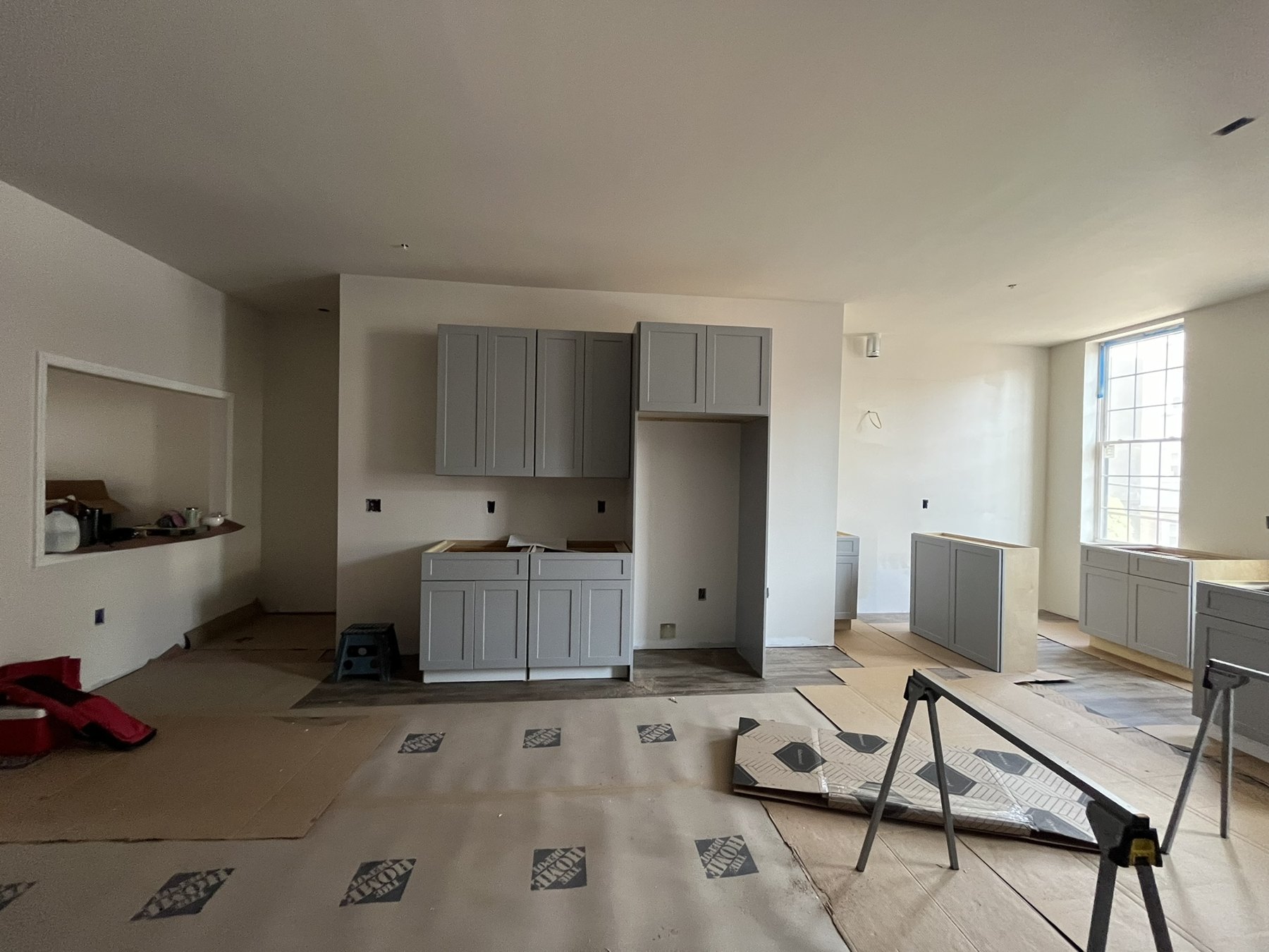 Kitchen cabinetry being installed in an unfinished room