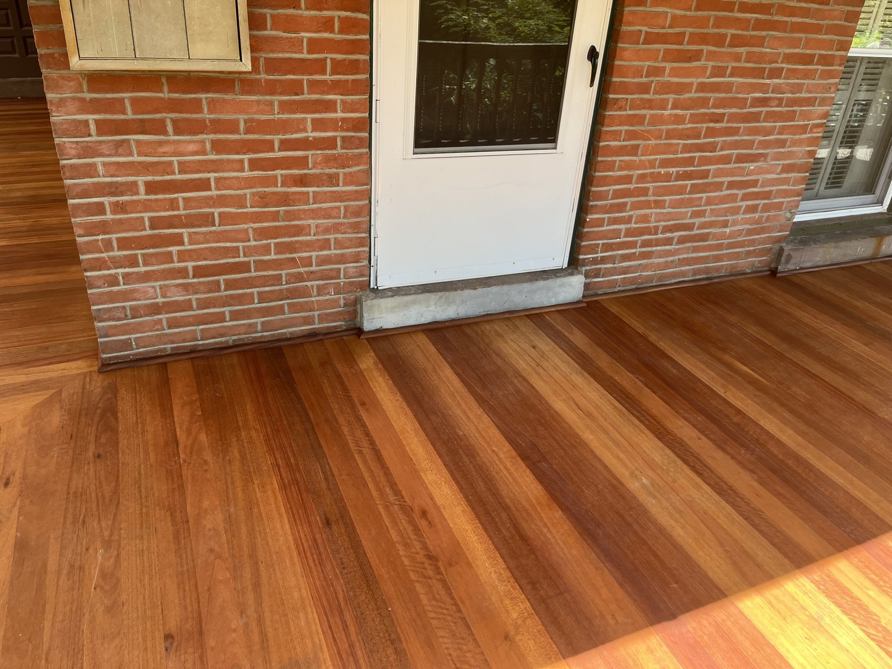 Renewed meranti porch decking alongside the brick house wall