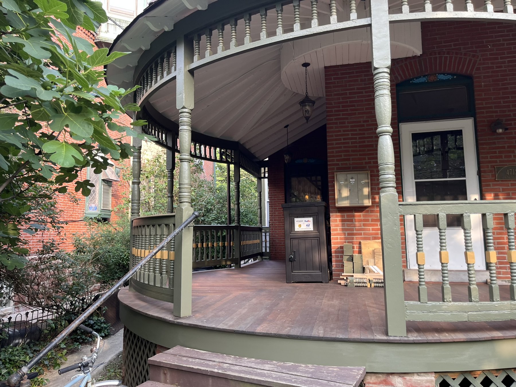 Restored curved porch entrance with turned posts, painted ornament, and wood decking