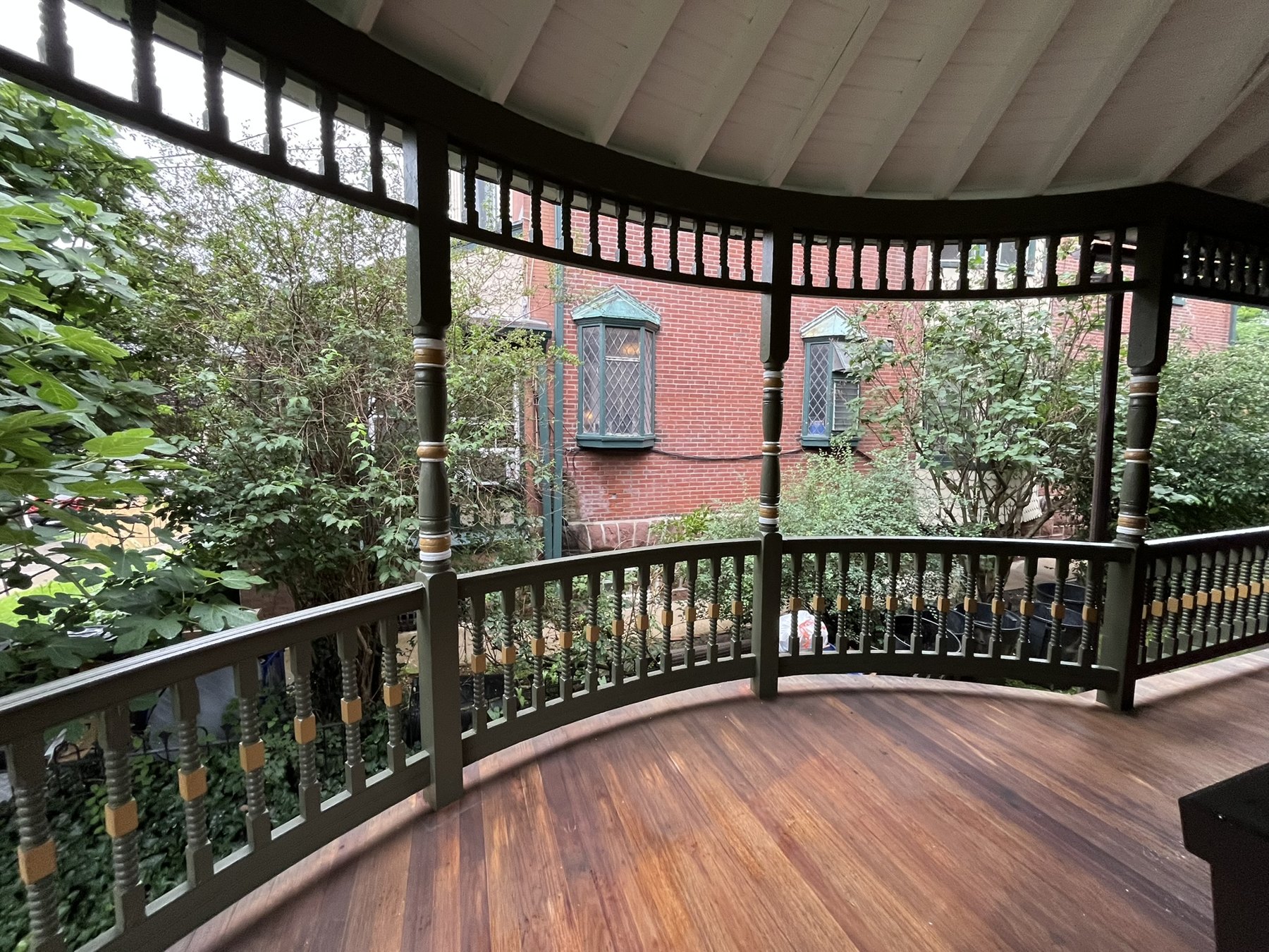 Curved porch corner with restored railings, painted ceiling, and meranti decking