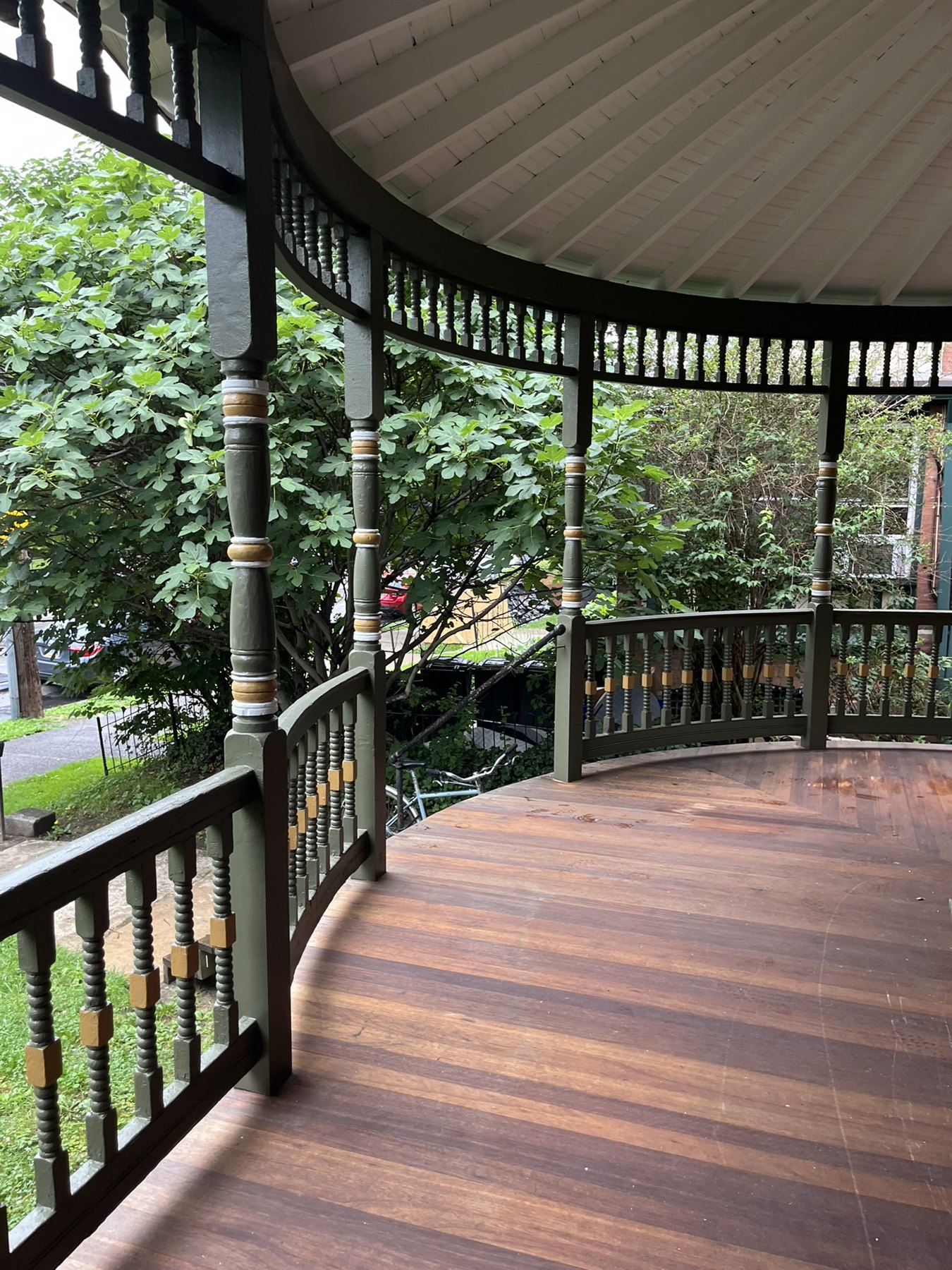 Finished meranti deck beneath restored green woodwork and a painted porch ceiling