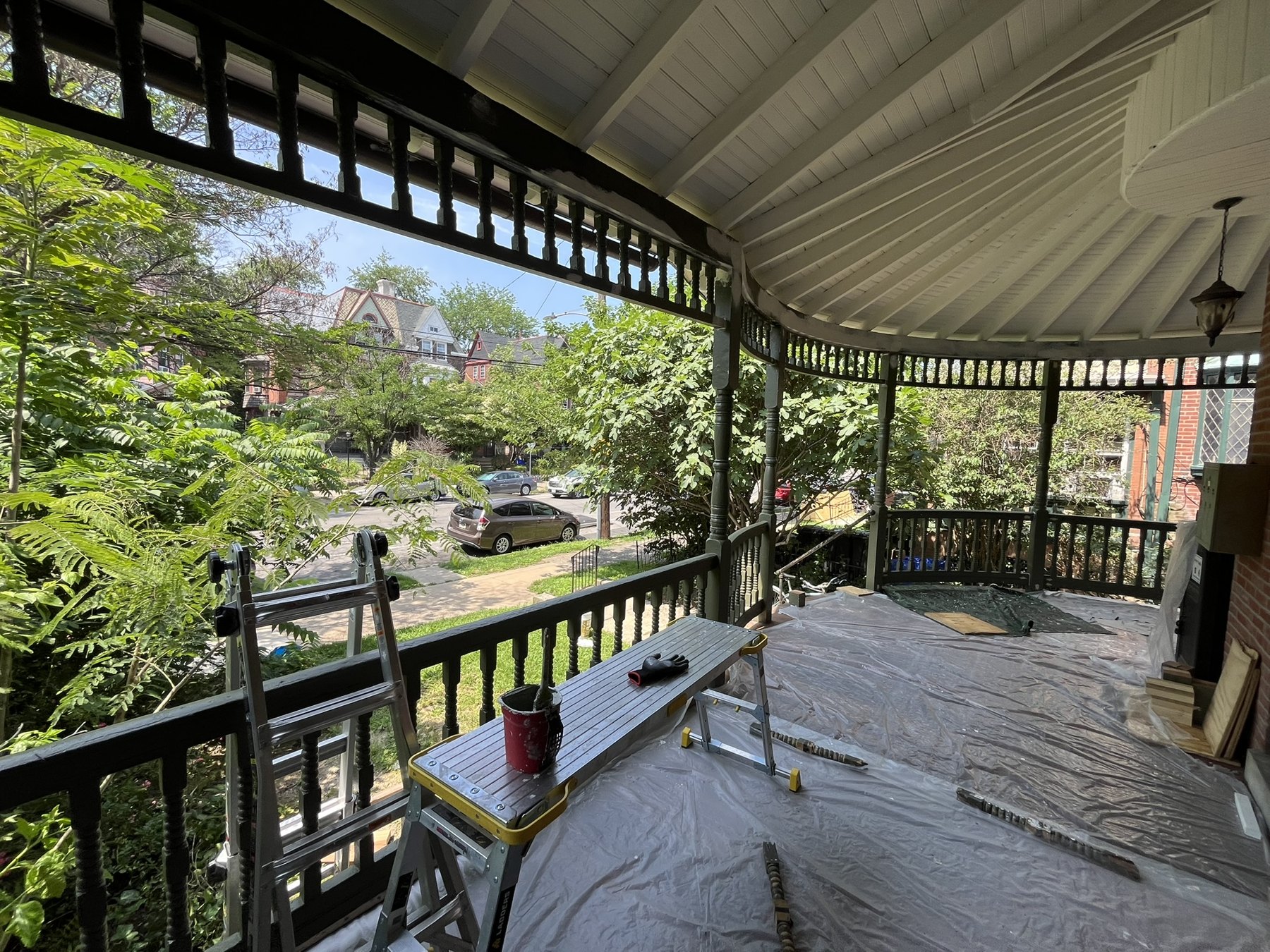 Porch during repainting with drop cloths, ladder, and painting supplies